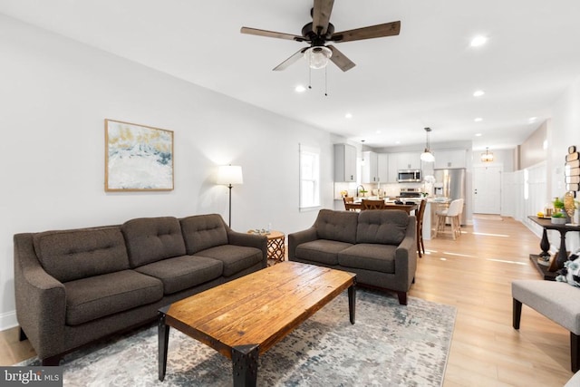 living room featuring light hardwood / wood-style floors and ceiling fan