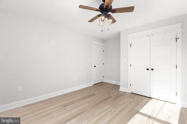 unfurnished bedroom featuring ceiling fan, light hardwood / wood-style floors, and a closet