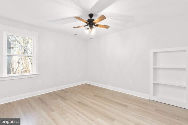 spare room featuring built in shelves, ceiling fan, and light hardwood / wood-style floors