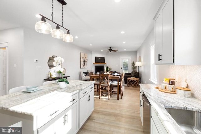 kitchen featuring light wood-type flooring, white cabinetry, hanging light fixtures, and a kitchen island