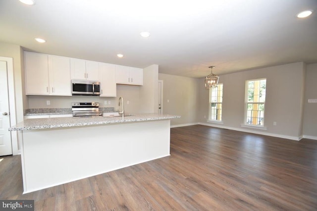 kitchen featuring dark hardwood / wood-style flooring, appliances with stainless steel finishes, white cabinets, and an island with sink