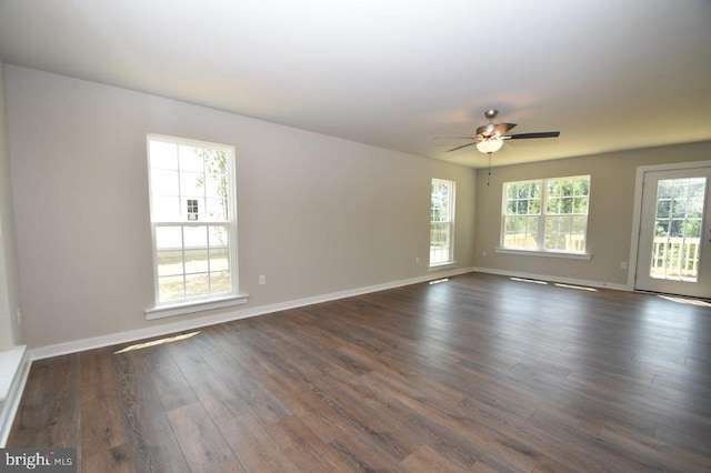 empty room with ceiling fan, a healthy amount of sunlight, and dark hardwood / wood-style flooring