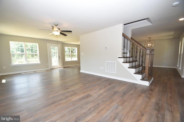 unfurnished living room featuring dark hardwood / wood-style flooring and ceiling fan with notable chandelier