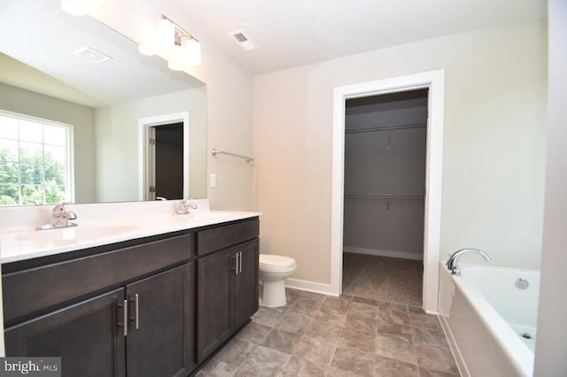 bathroom featuring vanity, a relaxing tiled tub, and toilet