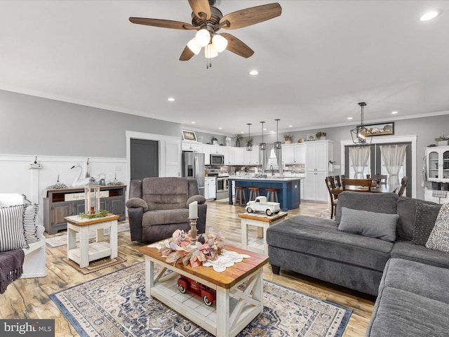 living room with light hardwood / wood-style floors, ceiling fan, and crown molding