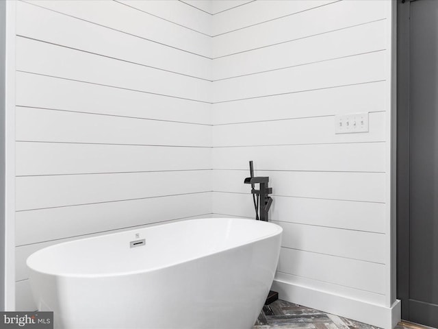 bathroom with a bathing tub and wooden walls