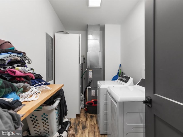 clothes washing area with electric panel, hardwood / wood-style flooring, and separate washer and dryer