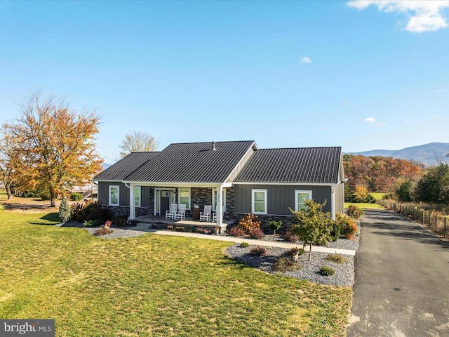 view of front of house with a front yard, a mountain view, and covered porch