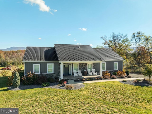 view of front of house featuring a porch, a front yard, and a mountain view