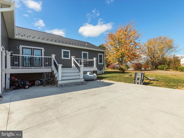 exterior space with a front yard, a wooden deck, and a patio area