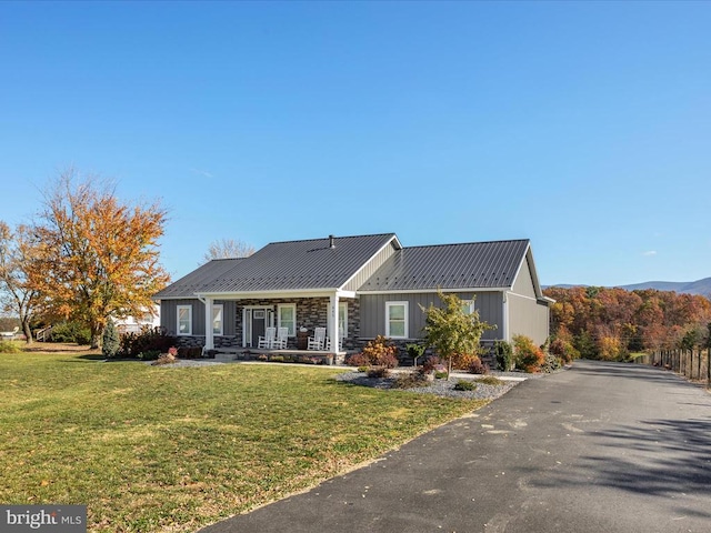 view of front of house featuring a porch, a front yard, and a mountain view