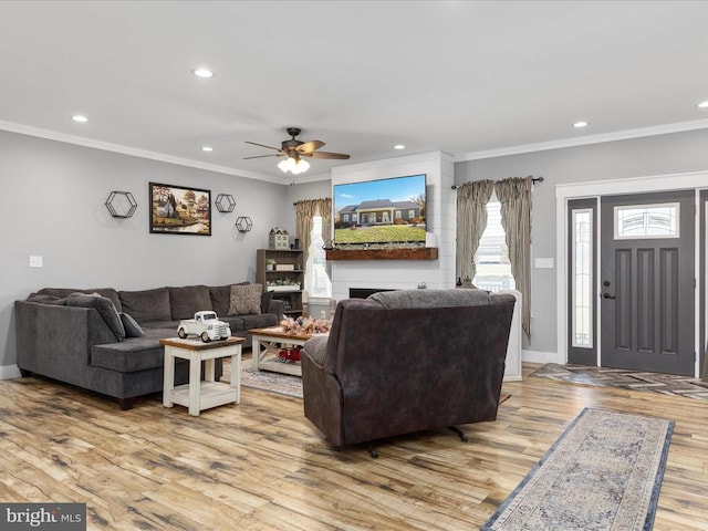 living room with ornamental molding, light wood-type flooring, and ceiling fan