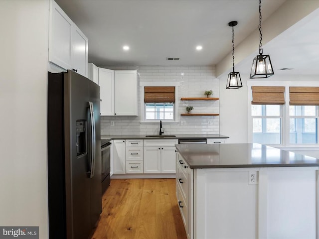 kitchen with white cabinetry, appliances with stainless steel finishes, light wood-type flooring, pendant lighting, and sink