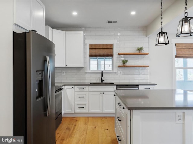 kitchen featuring white cabinets, appliances with stainless steel finishes, hanging light fixtures, and a healthy amount of sunlight