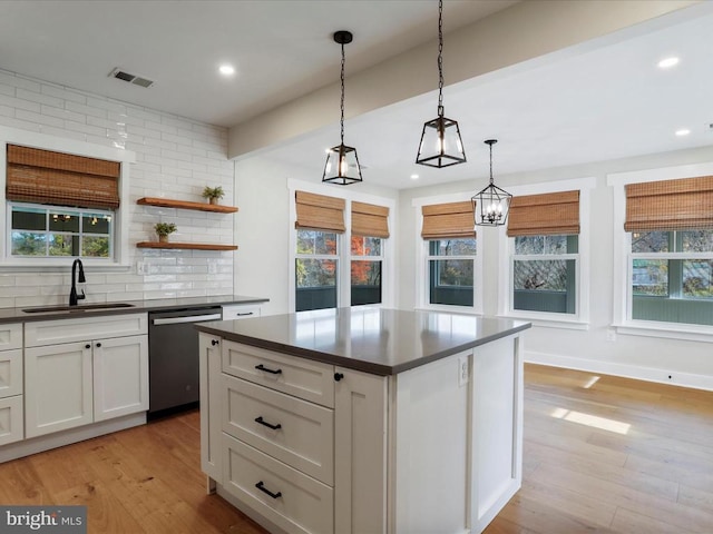 kitchen featuring white cabinetry, stainless steel dishwasher, decorative light fixtures, and sink