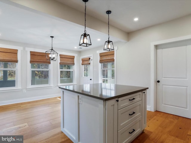 kitchen featuring light wood-type flooring, hanging light fixtures, a center island, and an inviting chandelier