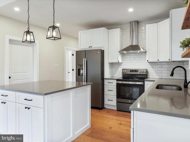 kitchen featuring stainless steel appliances, a kitchen island, white cabinetry, sink, and wall chimney exhaust hood