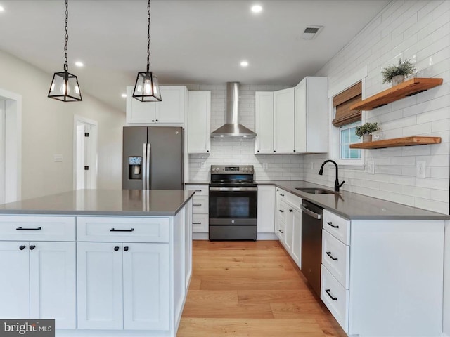 kitchen with pendant lighting, white cabinetry, wall chimney range hood, and appliances with stainless steel finishes