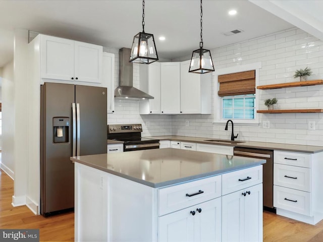 kitchen featuring white cabinetry, sink, appliances with stainless steel finishes, a kitchen island, and wall chimney range hood