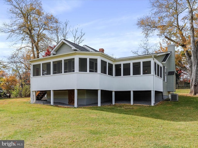 back of house featuring a sunroom, central AC, and a yard