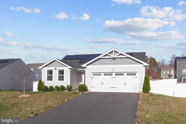 view of front of home featuring a garage, solar panels, and a front yard