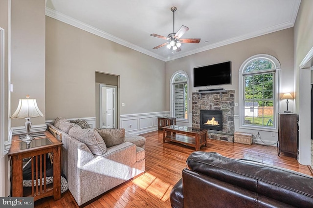 living room with wood-type flooring, a stone fireplace, and ornamental molding