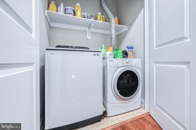 laundry area featuring washing machine and clothes dryer and hardwood / wood-style flooring