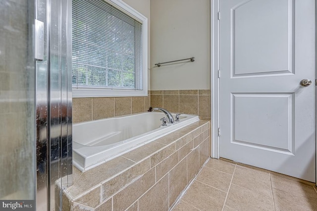 bathroom with tile patterned flooring and tiled bath