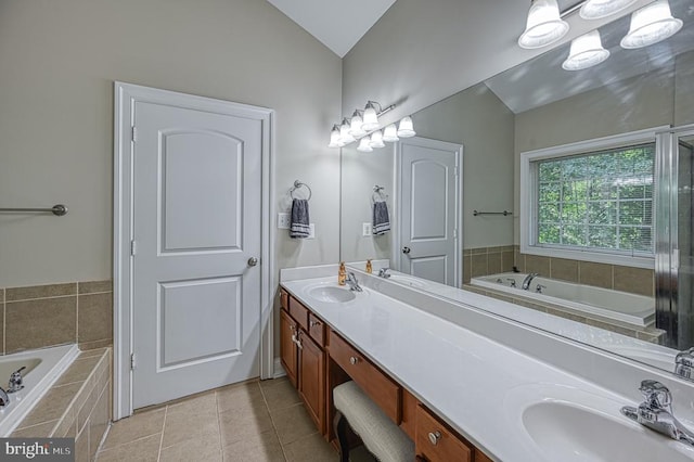 bathroom featuring tile patterned flooring, vanity, tiled bath, and vaulted ceiling