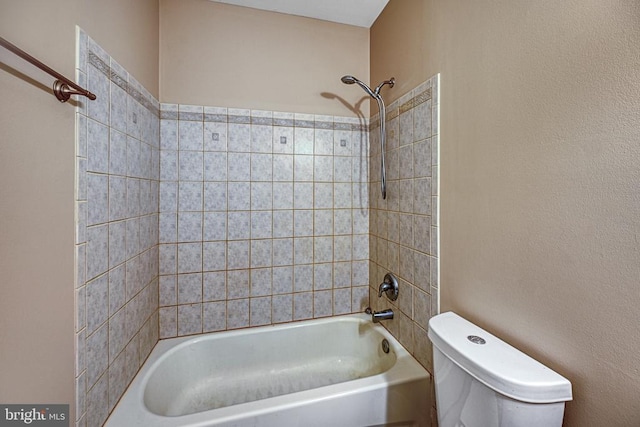 bathroom with toilet and tiled shower / bath