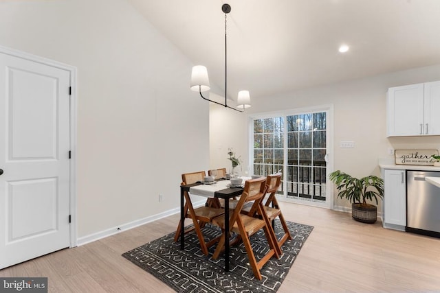 dining space with a chandelier, light wood-type flooring, and vaulted ceiling