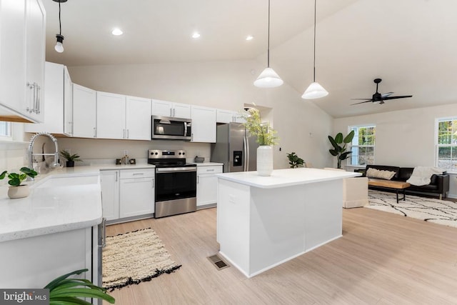 kitchen featuring stainless steel appliances, white cabinets, ceiling fan, light hardwood / wood-style flooring, and decorative light fixtures