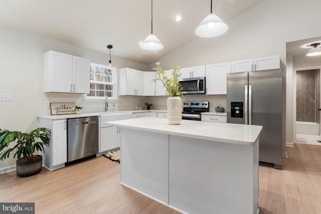 kitchen featuring stainless steel appliances, hanging light fixtures, white cabinets, and vaulted ceiling