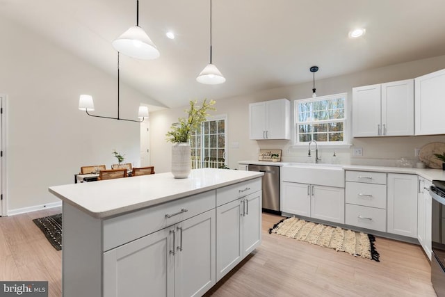 kitchen featuring a center island, white cabinets, stainless steel dishwasher, light hardwood / wood-style flooring, and decorative light fixtures