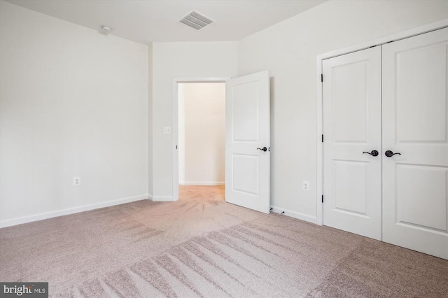 unfurnished bedroom featuring a closet and light carpet