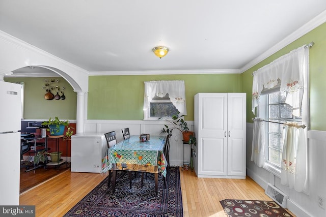 dining area featuring light hardwood / wood-style flooring, a wealth of natural light, and crown molding