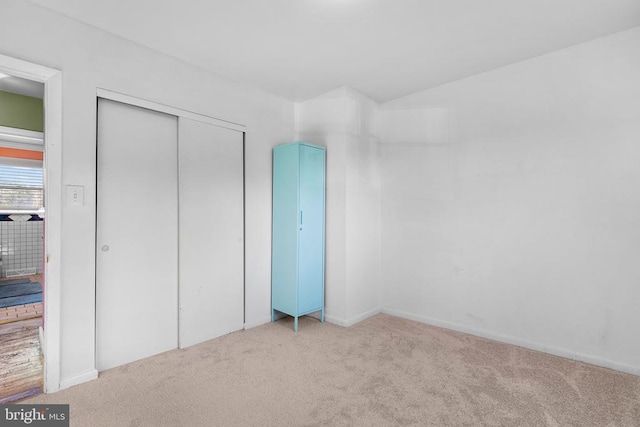 unfurnished bedroom featuring light colored carpet and a closet