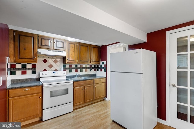 kitchen featuring light wood-type flooring, white appliances, sink, and tasteful backsplash