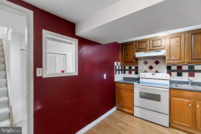 kitchen with light wood-type flooring, electric range, tasteful backsplash, and sink