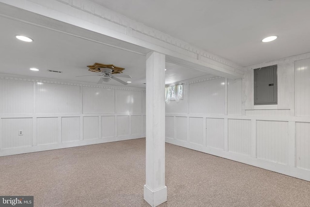 basement featuring ceiling fan, light colored carpet, and electric panel