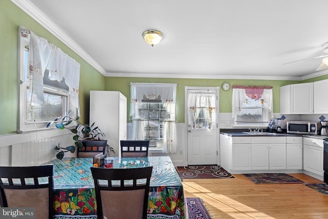 kitchen with white cabinets, sink, crown molding, and light hardwood / wood-style flooring