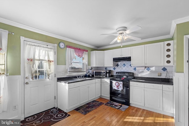 kitchen featuring black range with electric stovetop, white cabinetry, sink, light wood-type flooring, and ornamental molding