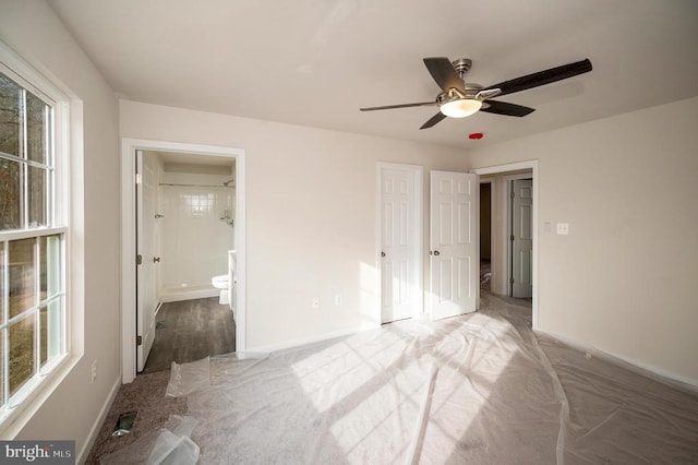 unfurnished bedroom featuring multiple windows, ceiling fan, carpet, and ensuite bathroom