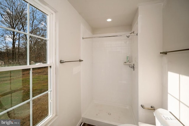 bathroom with a tile shower and toilet