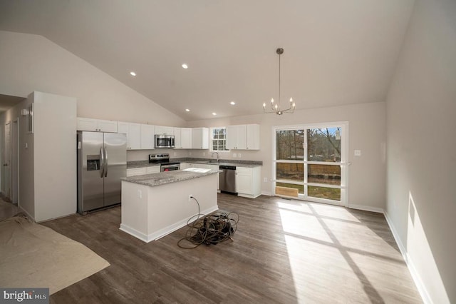 kitchen with a center island, light stone counters, hardwood / wood-style floors, pendant lighting, and appliances with stainless steel finishes