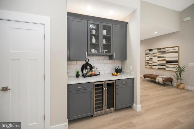 bar featuring gray cabinetry, decorative backsplash, wine cooler, and light hardwood / wood-style flooring