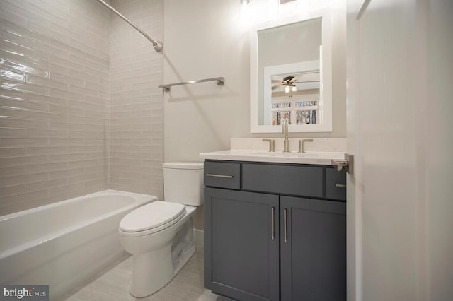 full bathroom featuring ceiling fan, toilet, tiled shower / bath, and vanity