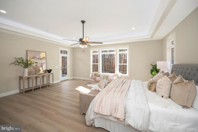 bedroom with hardwood / wood-style flooring, ceiling fan, and a tray ceiling