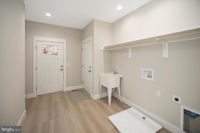 laundry area with electric dryer hookup, light hardwood / wood-style floors, sink, and hookup for a washing machine