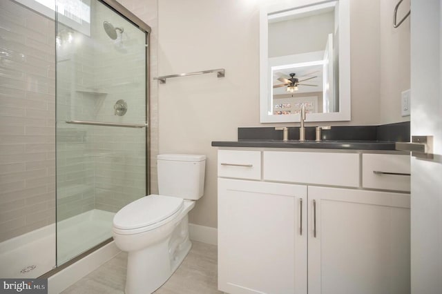 bathroom featuring ceiling fan, toilet, walk in shower, and vanity